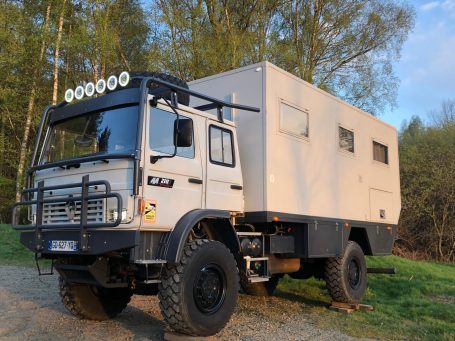Camion tout-terrain aménagé avec caisse mobile, équipé de phares sur le toit.